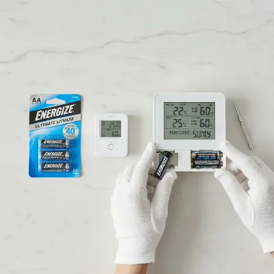 Close-up of new batteries and weather station components, emphasizing maintenance and battery care. 